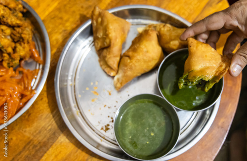 people enjoying indian traditional snack samosa with green chutney