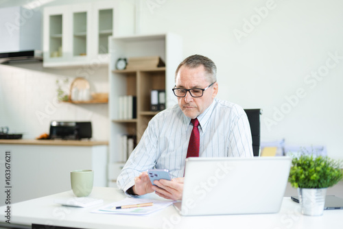 Wallpaper Mural Focused senior businessman holding a document and using calculator at modern office desk, analyzing finance, budget, and corporate planning data with coffee beside. Torontodigital.ca