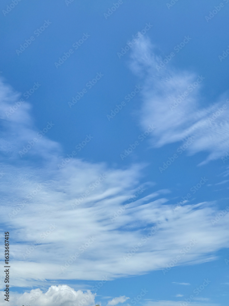 Obraz premium Clear blue sky with soft white clouds scattered across the frame, for background or nature themes