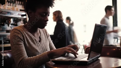 Person working on laptop in coffee shop daytime interior shot