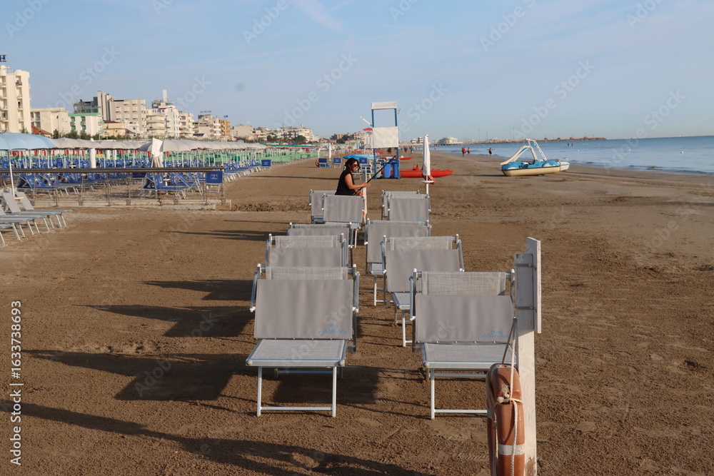 Obraz premium Beach worker preparing deckchairs on the beach in the morning