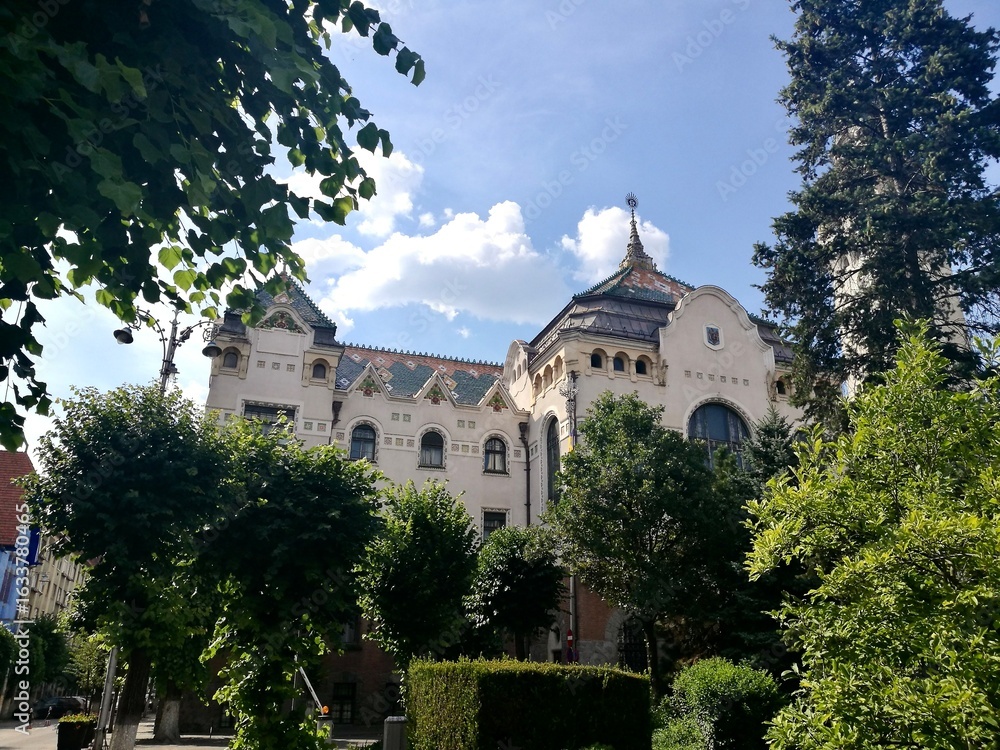 Fototapeta premium Palace of Culture in Targu Mures, Romania, features an intricately designed facade with decorative elements and ornate rooftop details. Its architecture blends Art Nouveau and Secession styles