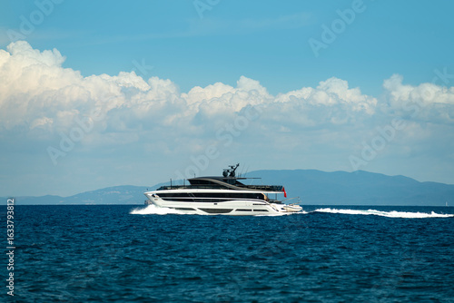 A luxury yacht sailing in the open sea with a background of withe clouds and blue sky