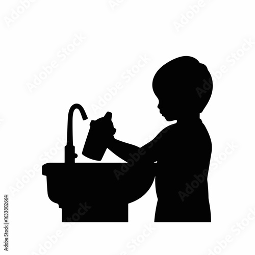 Child washing sippy cup beside sink, playful exploration