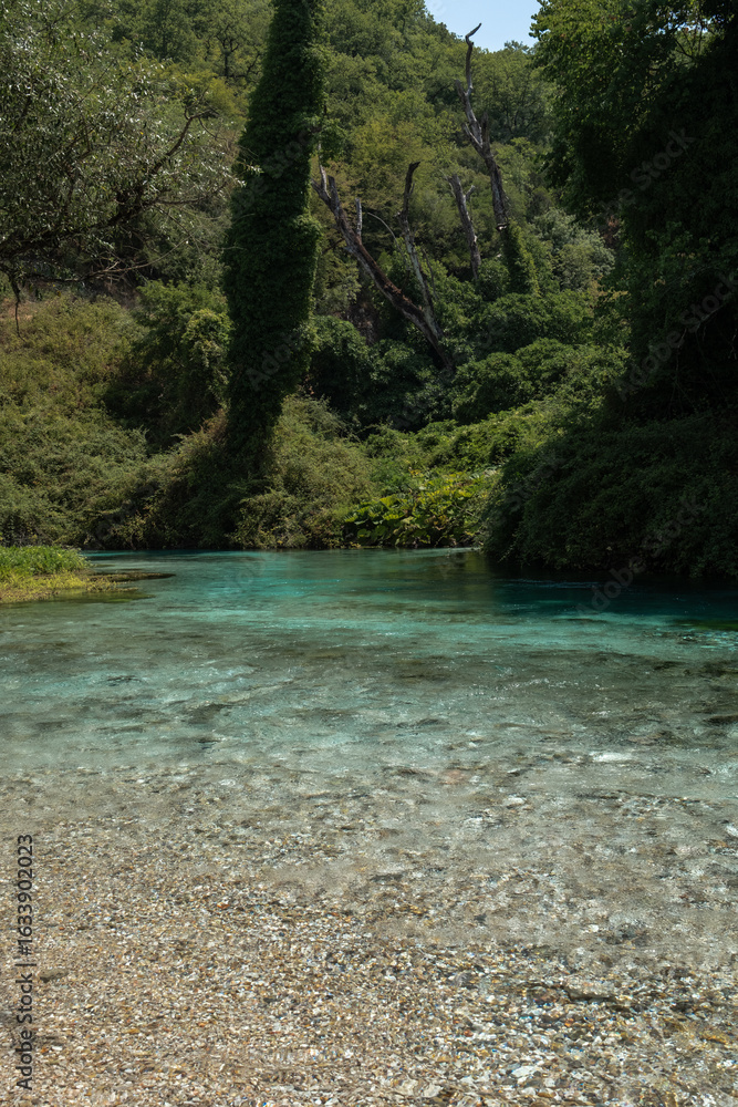 Fototapeta premium Vertical photo of Blue Eye spring (Syri i Kalter) in southern Albania, featuring turquoise water, forest surroundings, and vibrant nature.