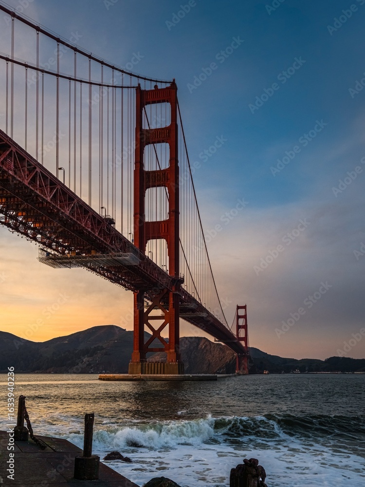 Obraz premium Golden Gate Bridge view from Fort Point with waves crashing on the shore