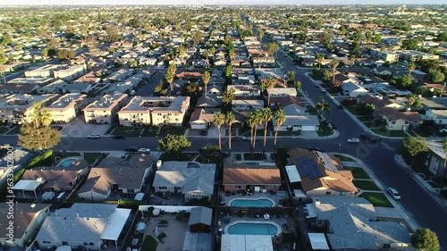 Aerial view showcases a dense suburban neighborhood with houses, streets, and palm trees under a clear sky