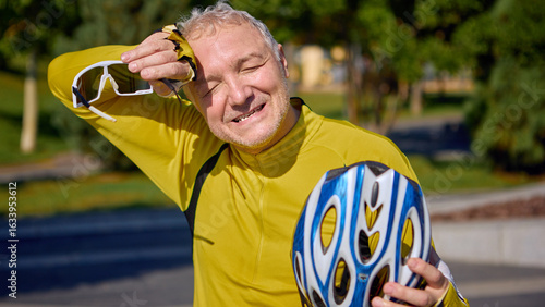 Photos Elderly male cyclist wiping sweat with glove after intense ride