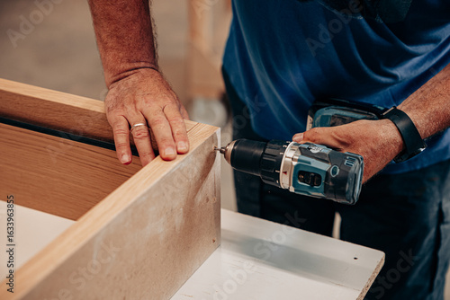 Billede på lærred Man Drilling Screws into MDF Cabinet for Assembly
