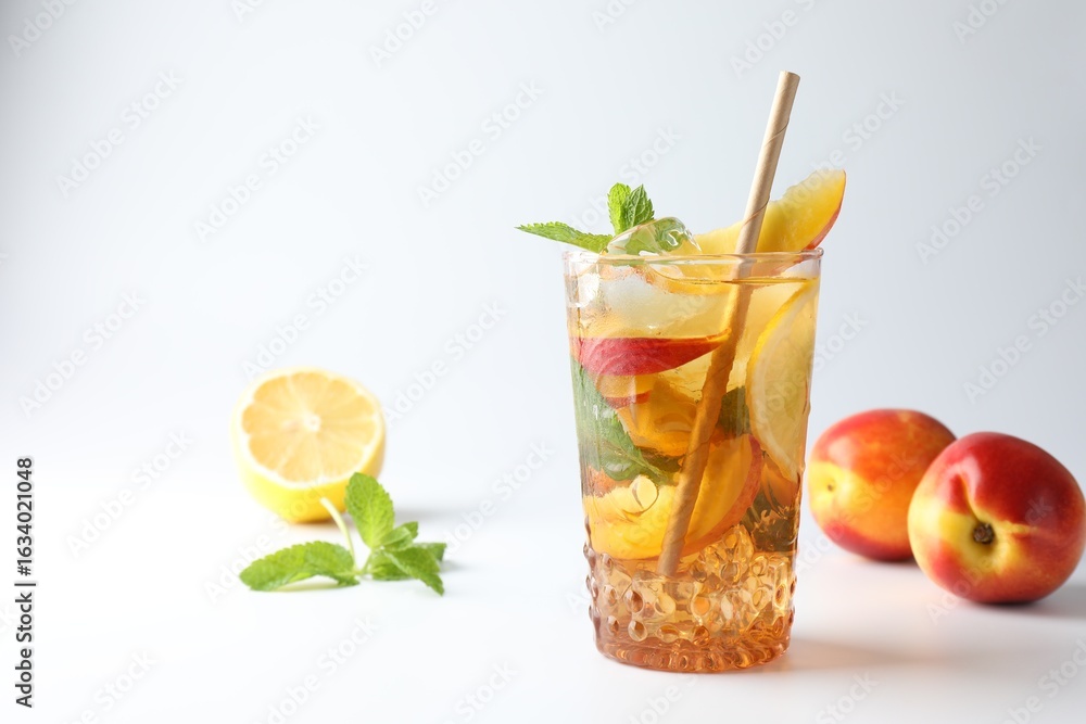 Fototapeta premium Tasty iced tea with lemon, peaches and mint on white background