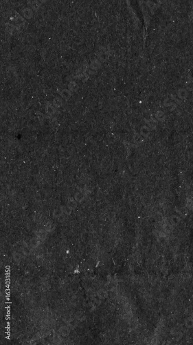 Black kraft paper noise texture vertical stop motion video. Old page overlay effect background loop animation. Vintage paper texture with crease, stain, grain, dust particles. Empty animated backdrop