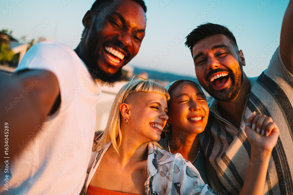 Obraz premium Happy friends laughing together at sunset on a rooftop party
