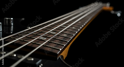 Close-Up View of an Electric Bass Guitar Fretboard with Shiny Strings under Dramatic Lighting