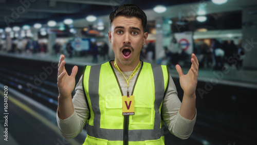 Fotografia Hispanic man wearing a reflective vest acts as a volunteer at a bustling indoor train station