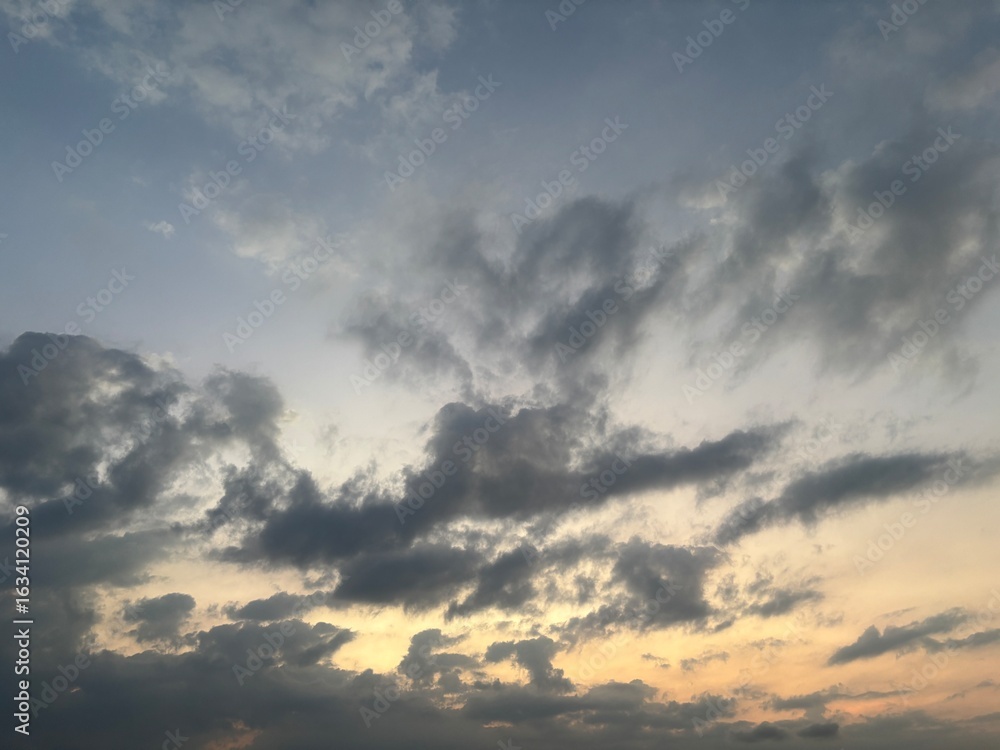 Obraz premium Dramatic sky at sunset with beautiful orange, blue, and grey clouds. A perfect natural background