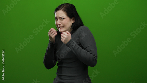 Woman expressing nervousness in green background setting, her emotions captured in vivid detail showing fear and uncertainty.