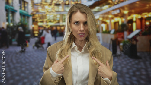Wallpaper Mural Woman gesturing on city street with relaxed expression, blonde hair, wearing beige jacket, surrounded by casual pedestrians and ambient, warm lighting in outdoor scene Torontodigital.ca