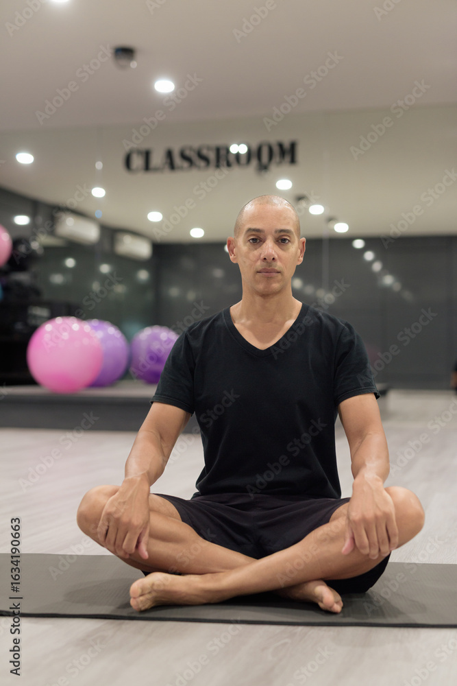 Fototapeta premium Hispanic bald man athlete in gym classroom doing yoga meditation while sitting