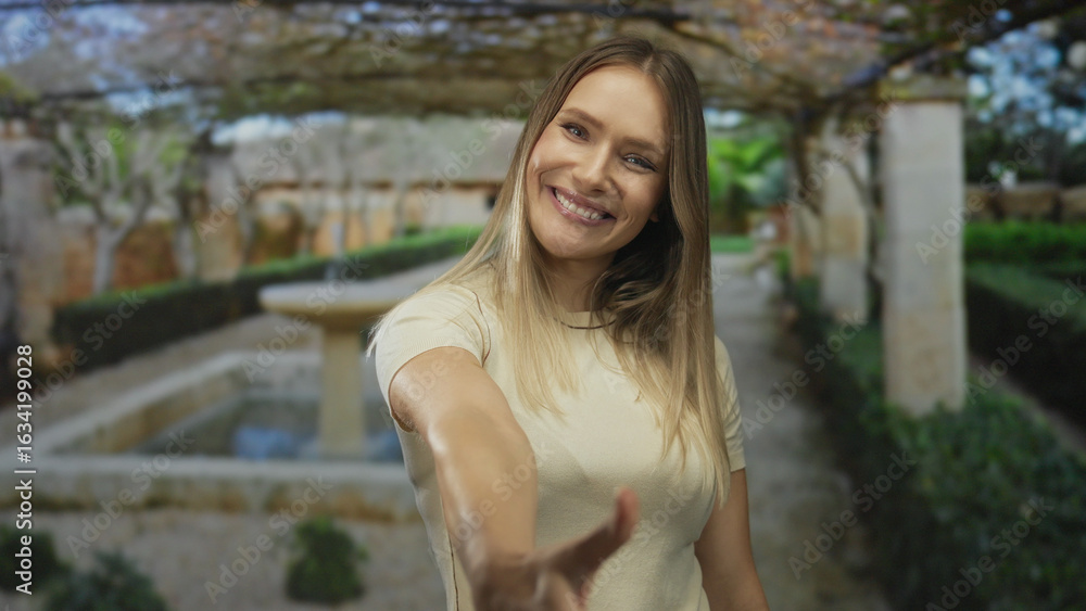 Woman smiling on city street reaches out for handshake conveying friendly connection in outdoor setting surrounded by urban greenery and architecture. Woman smiling on city street reaches out for handshake conveying friendly connection in outdoor setting surrounded by urban greenery and architecture.