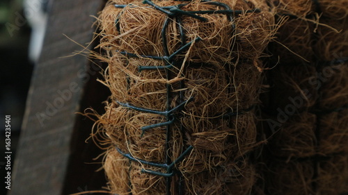 Quadro su tela Close-up of stacked coir fiber mats, bound together with green plastic ties, showing the texture and material of the natural fiber