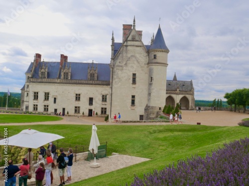 Scène de tourisme estivale et floue devant un château historique français.