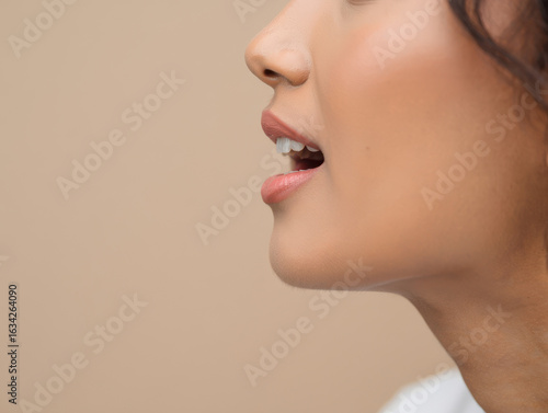 Captivating close-up profile of a woman's mouth speaking with clear white teeth and subtle lip gloss, conveying communication and expression
