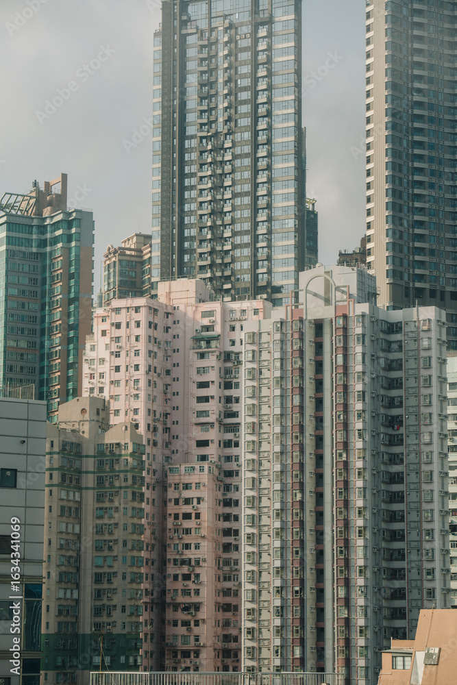 Fototapeta premium Dense cityscape with towering apartment buildings in Hong Kong. A mix of modern and older structures dominates the skyline.