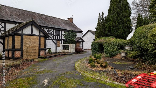Abandoned Deanwater Hotel near Manchester. Derelict tudor style white house boarded up. Vacant rural BnB on country lane, foreclosed in disrepair. Traditional British home, driveway, landscaped garden