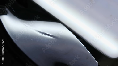 Small thin dent on special surface of smooth automobile body. Unevenness provides evidence car comes into contact with sharp object