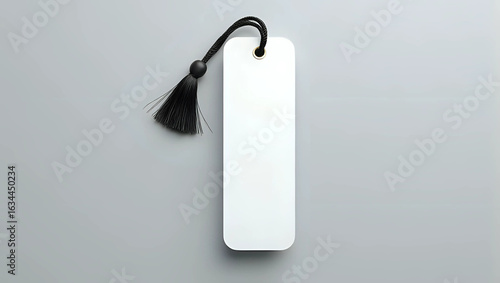 A blank white bookmark template with elegant black tassel, isolated on gray background - diy craft project or product mockup for personalized gifts and stationery concept 