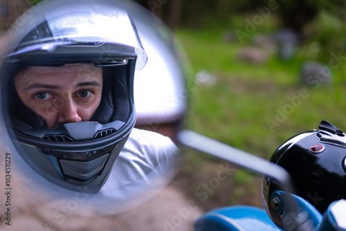 Canvastavla A motorcyclist wearing a helmet looks into the rearview mirror