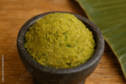 Thai Green Curry Paste in Stone Mortar with Banana Leaf Background