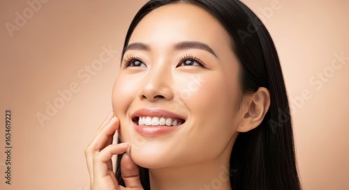 Closeup portrait of a beautiful young asian woman with glowing skin, smiling and looking up with a happy expression, soft studio lighting