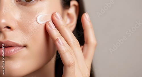 Closeup of a woman applying moisturizing cream to her cheek, promoting healthy, hydrated skin and a natural beauty glow