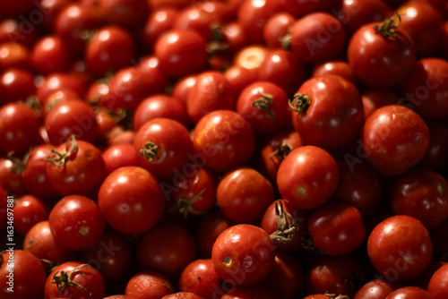 Fotografía Heap of fresh cherry tomatoes with stems attached, filling the frame in warm store lighting