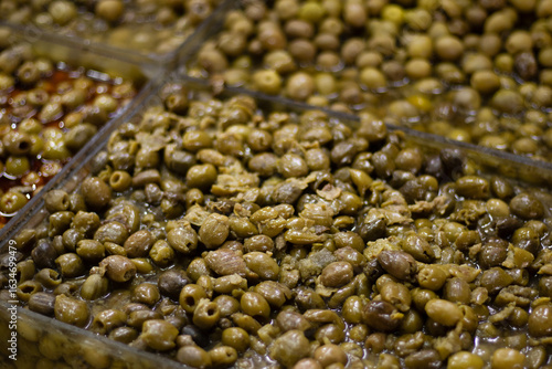 фотографія Compartmented tray of small green olives soaking in clear brine at a market bar