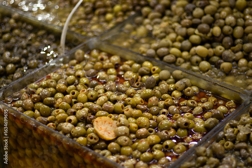 Obraz na plátně Compartmented tray of small green olives soaking in clear brine at a market bar