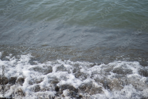 Photography Tight view of a small shore-break washing over wet beige sand
