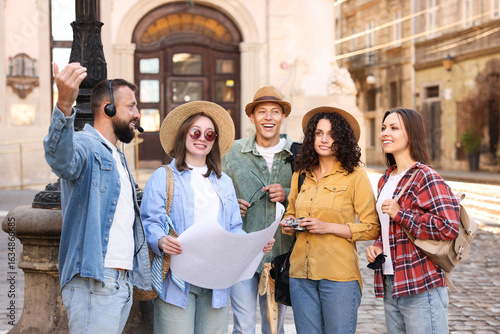 Slika na platnu Guide with headset and group of tourists on city street during excursion