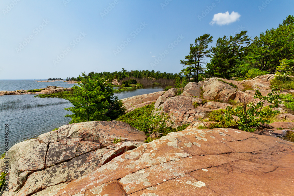 Naklejka premium Chikanishing trail. Red granite rocks on the north shore of Georgian Bay. Lake Huron. Killarney Provincial Park, Ontario, Canada.