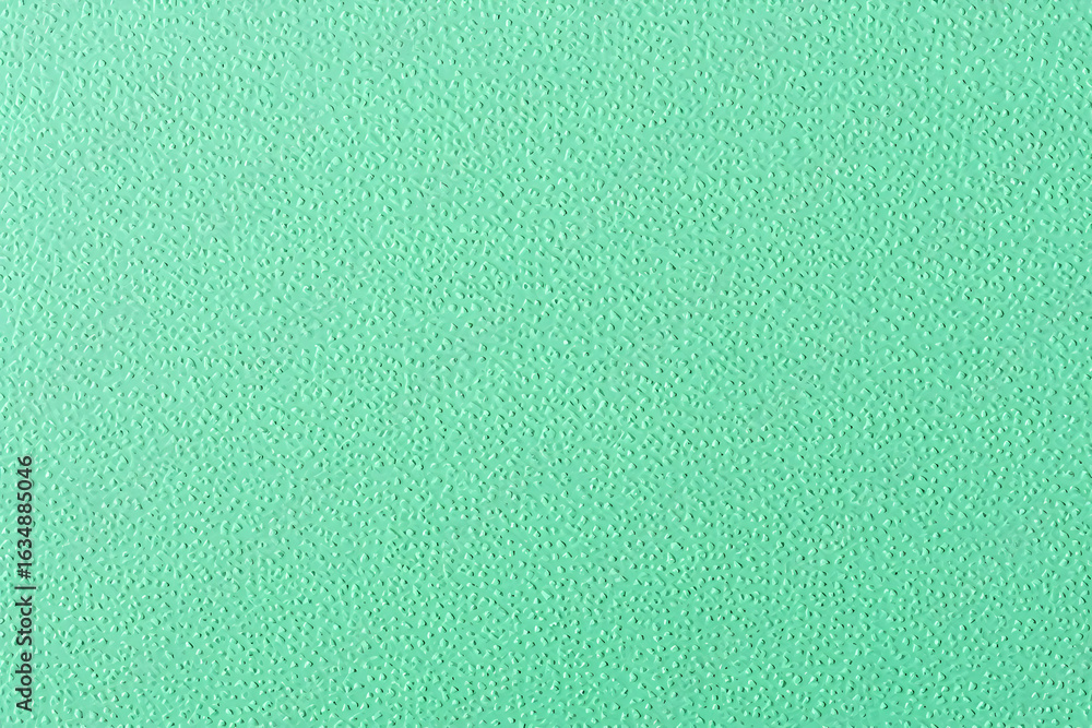 Fototapeta premium Close-up of a mint green textured background. A detailed macro view of a solid pastel surface with a fine, pebbled grain.