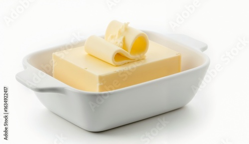Fresh butter block with curls in white dish on white background with copy space