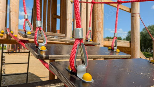 Obraz na plátně Wooden playground with a suspended rope bridge features red ropes and wooden planks