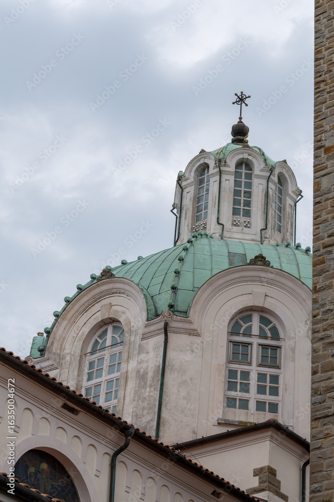 Obraz premium The green copper dome and arched windows of the Marian Sanctuary on Barbana Island, standing tall against a moody sky near Grado, Italy.