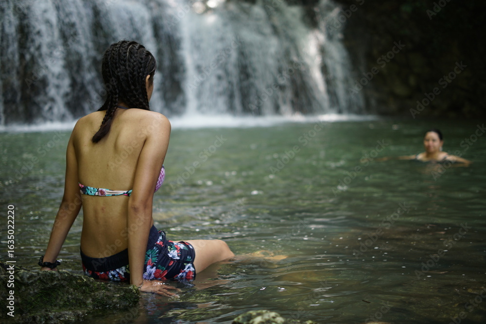 Fototapeta premium Female tourists exploring Siete Altares, which is a natural attraction located near Livingston, Guatemala, featuring seven freshwater pools and waterfalls set within a lush rainforest.