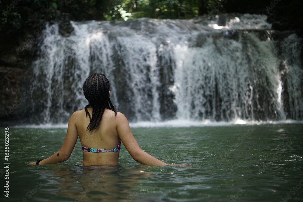 Fototapeta premium Female tourists exploring Siete Altares, which is a natural attraction located near Livingston, Guatemala, featuring seven freshwater pools and waterfalls set within a lush rainforest.