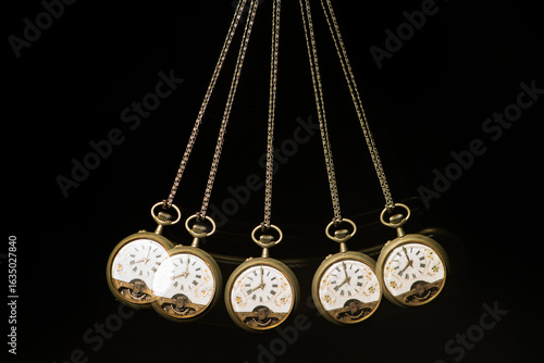 Photos Antique pocket watch moving on a pendulum creating the illusion of multiple clocks, black background, selective focus