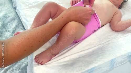 Mother changes textile multiple eco diapers to newborn baby.Little infant girl on changing table in eco friendly nappy.Mom taking care of child,motherhood daily routine.no waste disposal concept