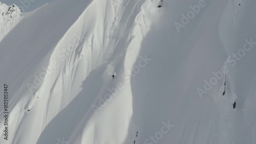Skier makes turns down large snow covered mountain peak in Alaska epic aerial shot