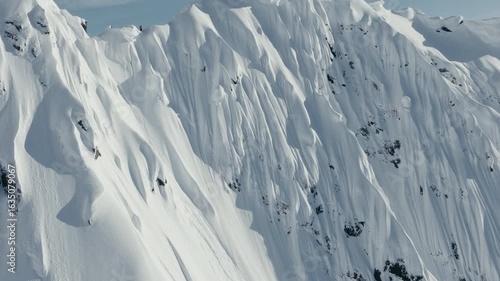 Skier makes turns down large snow capped peak in Alaska epic aerial shot
